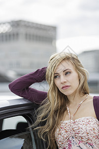 年轻女人靠在城市的汽车旁边图片
