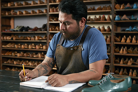 手工鞋店的工匠使用记事本登记图片