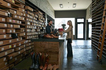 在传统鞋店为女客户服务的服务员图片