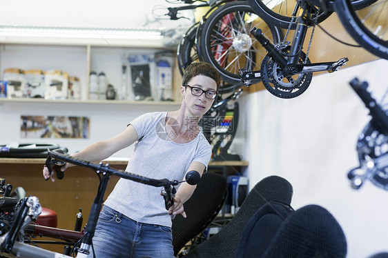 自行车修间的妇女检查骑自行车的车把图片