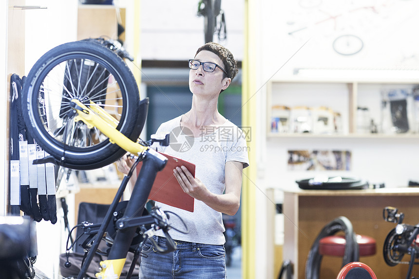自行车工作坊的妇女检查轮胎图片