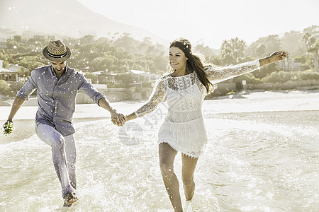 在南非开普敦的海边牵手奔跑的夫妇图片