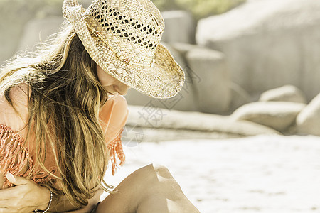 在海滩上坐在戴草帽的妇女图片