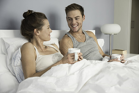 在床上喝咖啡的年轻夫妇图片