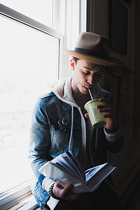 在家坐在窗台上喝水阅读书的年轻人图片