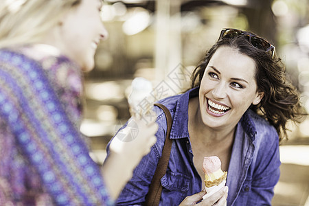 女人拿着冰淇淋甜筒看着朋友微笑图片