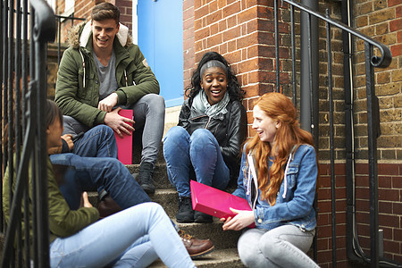 年轻大学生朋友在校园楼梯上聊天图片