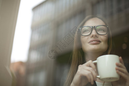 咖啡店窗口拿着咖啡杯的女商人图片