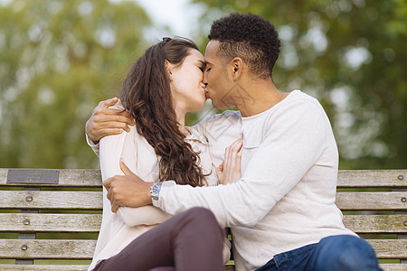 在公园长椅上接吻的年轻夫妇图片