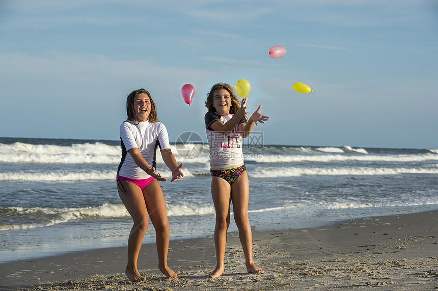 两个年轻姐妹在海滩上玩气球图片