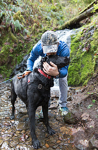 男人在溪流旁亲吻爱犬图片