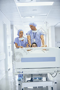 身着外科手术服的医生推着躺在病床上的病人图片