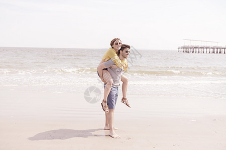 男子背着妻子行走在海滩上图片