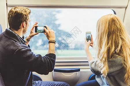 在意大利火车厢窗口拍摄智能手机照片的年轻夫妇图片