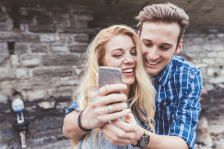 意大利科莫湖使用智能手机自拍的年轻夫妇图片