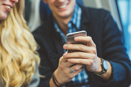 年轻夫妇在火车上阅读智能手机短信的特写图片