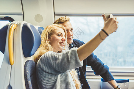 年轻夫妇在火车上使用手机自拍图片