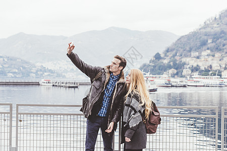 意大利科莫湖边使用手机自拍的年轻夫妇图片