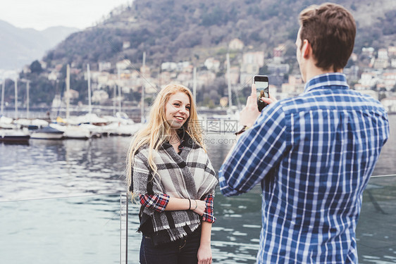 意大利科莫湖海滨给女友拍照的青年男子图片