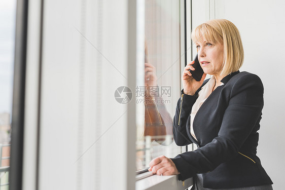 在窗边打电话的女人图片