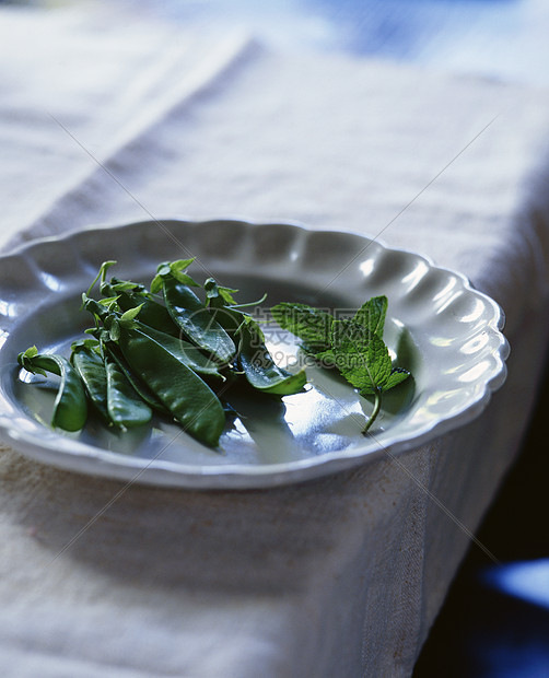 白色盘子上糖糊豆和薄荷图片