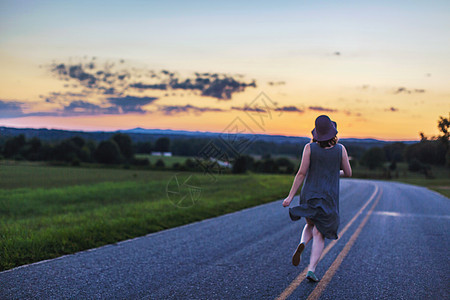 日落时女人沿农村道路跑着图片