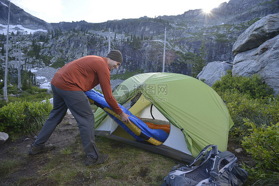 日落断湖塞尔基克山脉爱达荷州的男子在搭帐篷图片