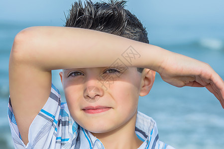 美国新泽西州阿斯伯里公园海滩上男孩保护眼睛的肖像图片
