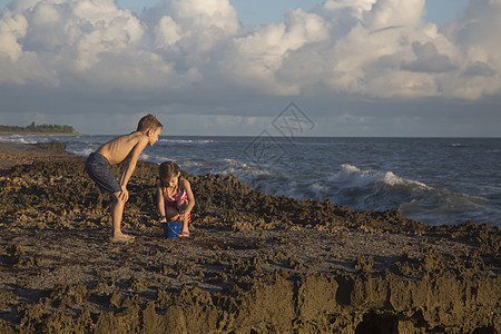 男孩和妹在海滩玩具桶美国佛罗里达州木星吹落岩保护区图片