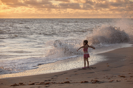 美国佛罗里达州朱庇特岛日出时海浪拍打岩石保护区张开双臂的女孩图片
