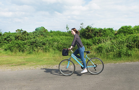 乡村车道上骑自行车的年轻女性图片
