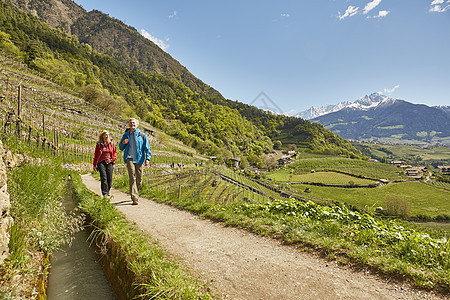 意大利南蒂罗尔梅兰一对成年夫妇沿着乡村公路徒步旅行图片