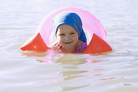 德国巴伐利亚州塞内尔西湖一名蹒跚学步的女孩戴着游泳圈在微笑图片