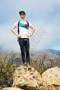 站在山顶石头上双手叉腰的成年男性图片