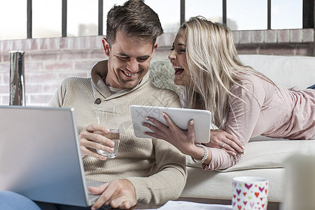 家里有几对夫妇男人用笔记本电脑女人拿着数字平板电脑笑着图片