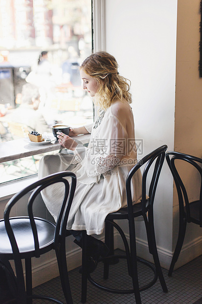 坐在咖啡店窗户座位上的妇女图片