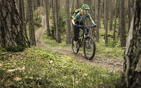 意大利南蒂罗尔州博森女子在林中骑自行车背景图片