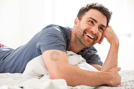 男人躺在床上手肘看着微笑图片