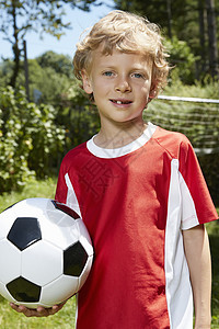 穿着足球制服的男孩在花园里足球的近距离肖像图片