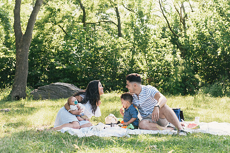 在美国纽约布朗克斯PelhamBay公园的野餐毯上父母与婴儿和幼子一起放松图片