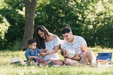 美国纽约州布朗克斯佩勒姆湾公园父母带着婴儿和蹒跚学步的儿子坐在一起图片