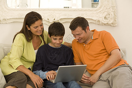 夫妇和儿子在沙发上浏览笔记本电脑图片