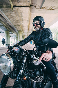 坐在摩托车上骑着的成熟男摩托车骑手图片