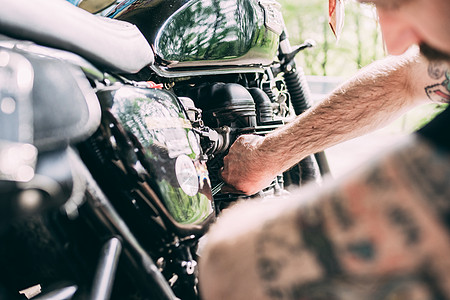 男摩托车手跪在修理摩托车上图片
