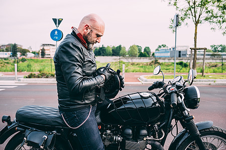 坐在摩托车头盔上的成熟男摩托车手图片