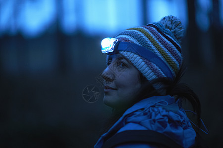 女登山者在夜间从森林上仰望肩膀图片