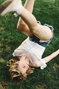 年轻女孩躺在草地上双腿腾空图片