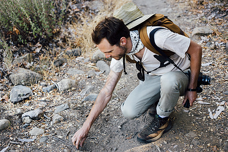 美国加利福尼亚州马里布峡谷徒步旅行者蹲着捡石头图片
