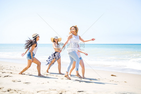 四位成年女朋友在美国加利福尼亚州马里布海滩上玩耍图片