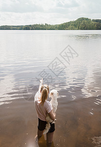 女人抱着狗站在水里图片